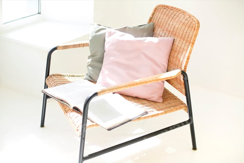 Preview: High angle of contemporary wicker armchair with soft cushions and opened book placed in living room