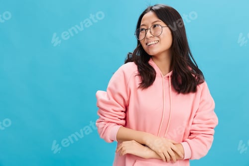 Preview: Cheerful cute Asian student young lady in pink hoodie sweatshirt wear round glasses look aside