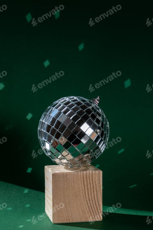 Preview: Disco ball with wooden cube reflecting sunlight, green background