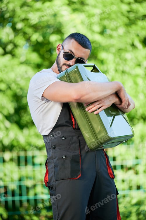 Preview: Handsome worker hugging tightly canister full of gasoline.