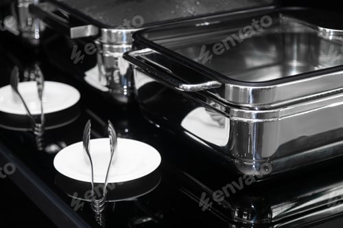 Preview: Black and white image of metal containers and tongs on the plate