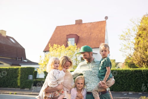 Preview: Family with children (18- 23 months, 4-5, 8-9 ) standing in in front of suburban house