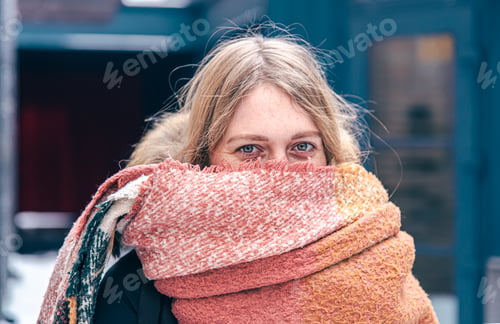 Preview: Portrait of a cute young woman wrapped in a scarf in winter.
