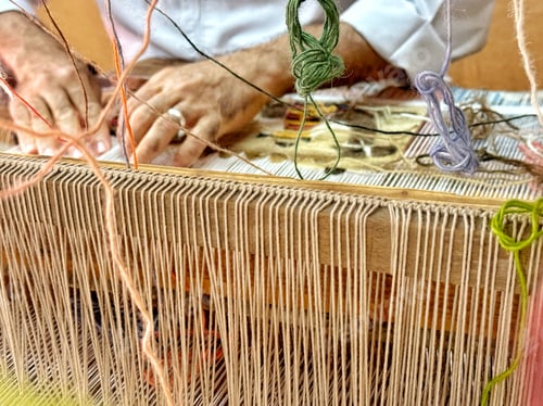 Preview: Closeup of a rug carpet weaving artisan using a loom to make an original colorful carpet with wool
