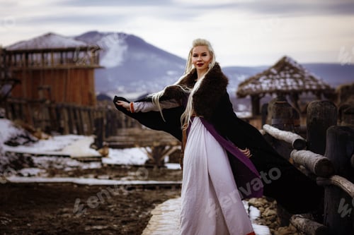 Preview: Beautiful blonde Viking dressed in a black cloak against the backdrop of the castle
