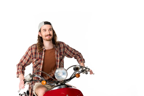 Preview: young man riding on red scooter and looking forward isolated on white