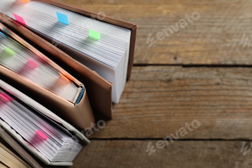 Preview: Books with colorful tabs on wooden table, above view. Space for text
