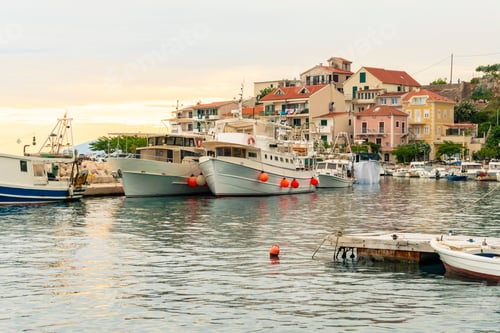 Preview: Coastal scene at dusk with moored boats and pastel-colored buildings under a cloudy