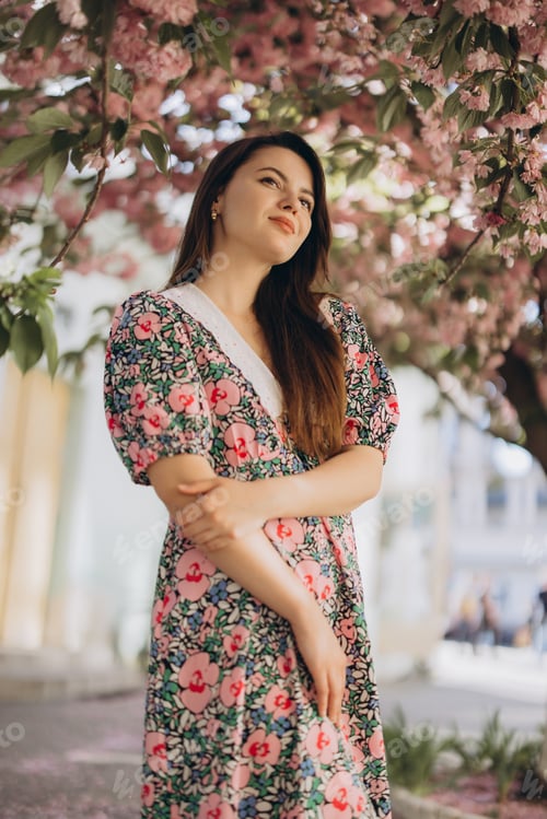 Preview: Young woman posing under blooming sakura tree enjoying spring season