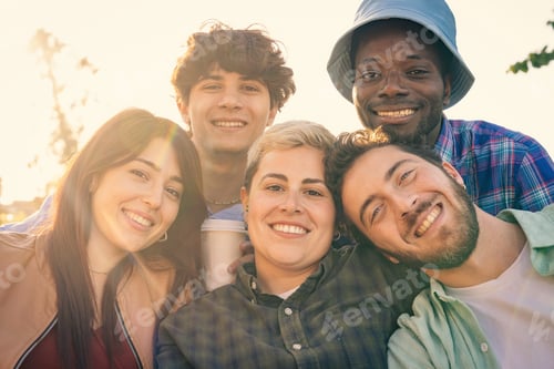 Preview: A happy diverse group of friends smiling together in the warm sunlight at sunset.