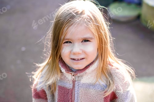 Preview: Smiling young girl wearing a stylish checkered jacket, posing for the camera with a blurred.