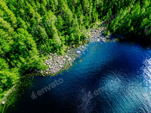 Preview: Aerial drone view of blue lake water with green tree woods on a sunny summer day in Finland