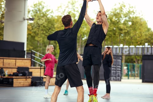 Preview: A group of cheerful young people girls and guys are discussing and debating while playing basketball