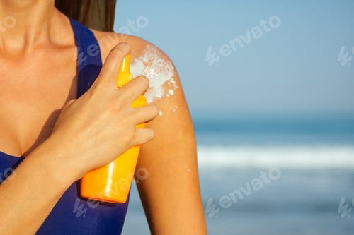 Preview: young woman in a blue swimsuit holding a plastic orange package spray bottle