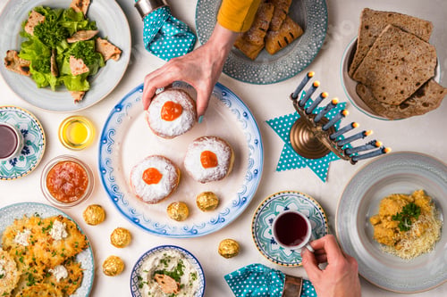 Preview: Jewish holiday Hanukkah, traditional feast, hands above table top view