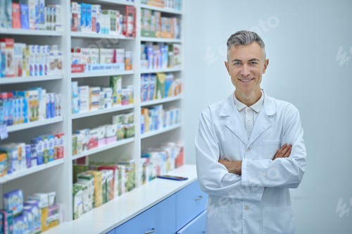 Preview: Joyful handsome pharmacist posing for the camera in the workplace