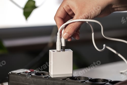 Preview: White USB charging for gadgets on a blurred background of the room, close-up.