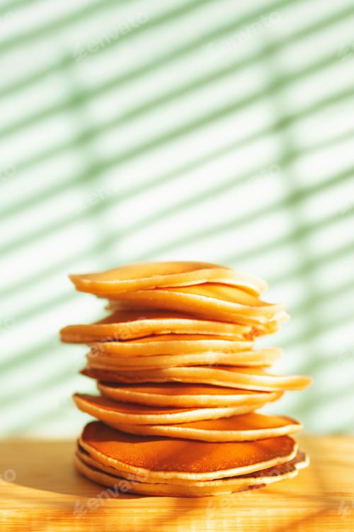 Preview: Stack of tasty pancakes on wooden desk against shadow background.