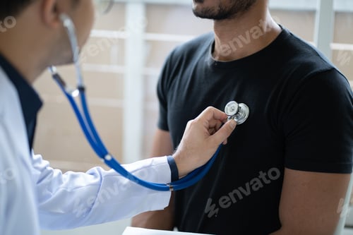 Preview: Young male doctor holding stethoscope examining his male patient in the clinic room