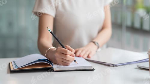 Preview: Image of a woman holding a pencil taking notes on the blank paper in the office.