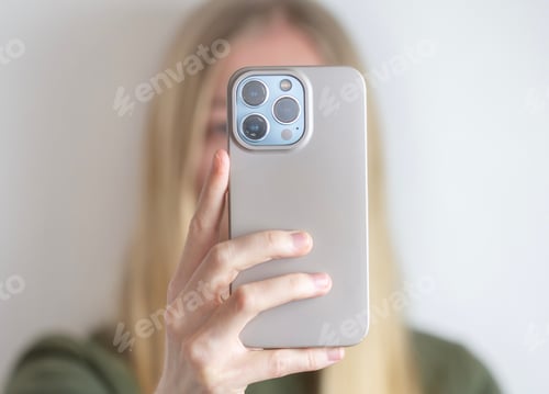 Preview: A young blonde woman or girl holding a phone, maybe taking selfie or video chat