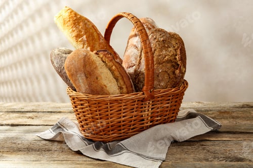 Preview: Different loaves of fresh bread in basket on wooden table, closeup