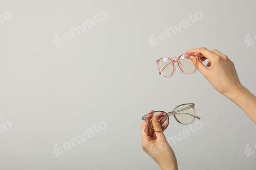 Preview: Glasses in female hands on light gray background, space for text