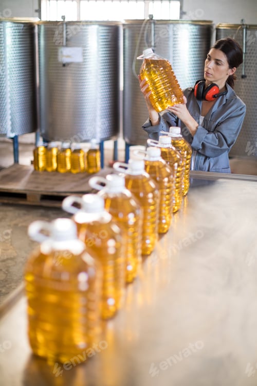 Preview: Female worker checking oil bottles