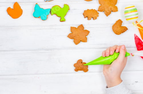 Preview: Girl decorating gingerbread with icing for Easter