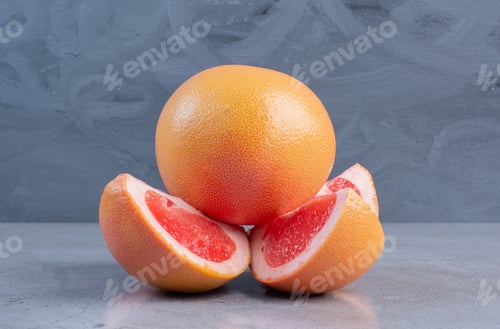 Preview: Sliced and whole grapefruits displayed on marble background