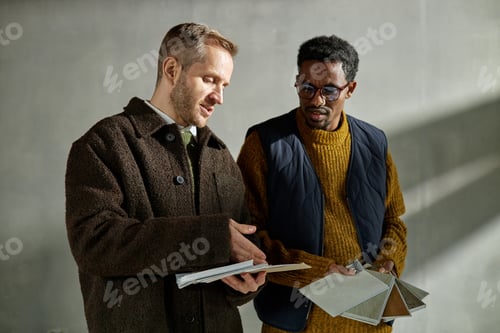Preview: Middle Aged Caucasian Man and Black Man Discussing Material Samples Indoors