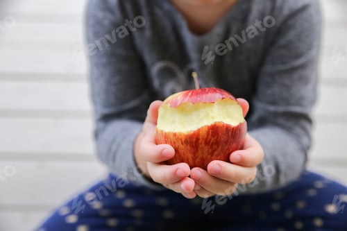 Preview: kid hands holding a red bitten apple, an apple a day keep the doctor away, health concept