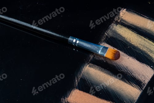 Preview: Makeup brush with powder samples on black background.