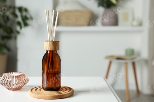 Preview: Aromatic reed air freshener and candle on white table in room. Space for text