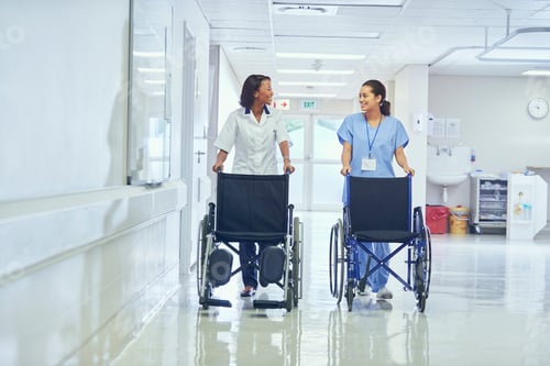 Preview: Female orderlies pushing wheelchairs along hospital corridor