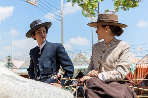 Preview: Focused man and woman in hats on horseback speaking in daylight against tents