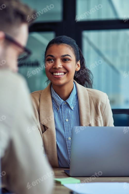 Preview: Vertical shot of a young cheerful mixed race female office worker working on laptop in the modern