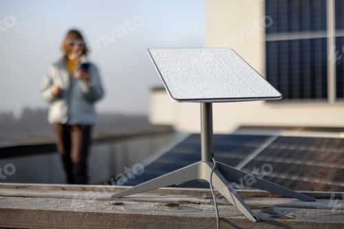Preview: Starlink satellite dish on roof of residential building and woman on background