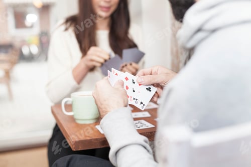 Preview: Two people enjoying a card game over coffee.