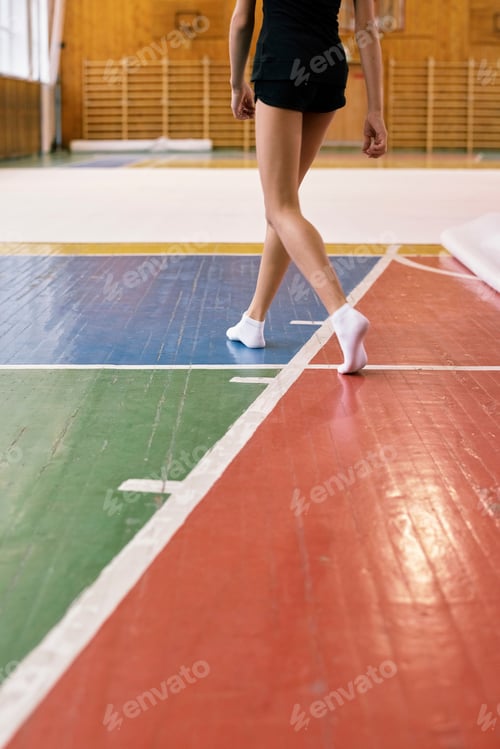 Preview: Teenage Caucasian Girl Practicing Gymnastics Routine on Indoor Sports Court