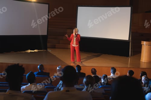 Preview: Businesswoman standing and giving presentation in auditorium