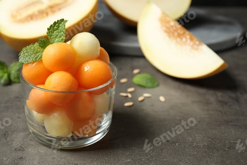 Preview: Melon balls and mint in glass on grey table, closeup. Space for text