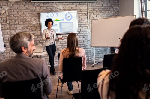 Preview: Businesswoman holding presentation to diverse group of people.