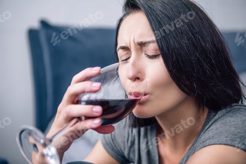 Preview: selective focus of lonely depressed woman drinking wine at home