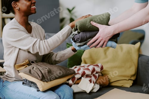 Preview: Black Woman Receiving Folded Clothes during Home Donation Sorting