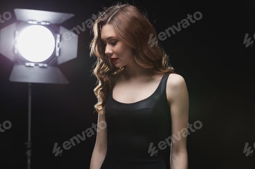 Preview: Beautfiul young woman standing near studio spotlight