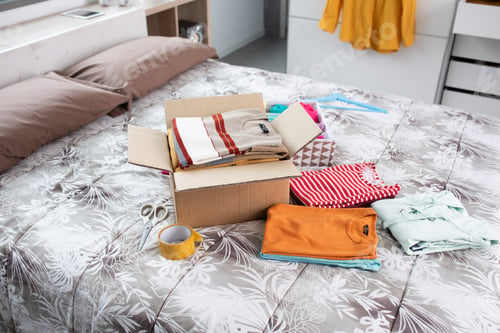 Preview: T-shirts and delivery box on the bed