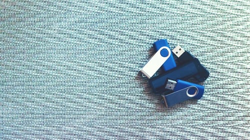 Preview: Many usb flashes on metallic textural background. Heap of plastic flash drives on metallic texture
