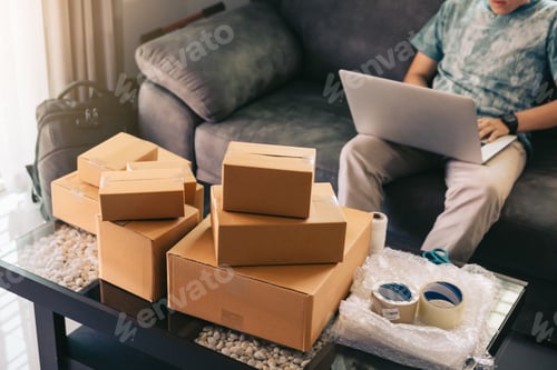 Preview: Asian teenager working in home office going over inventory and shipping on desk.