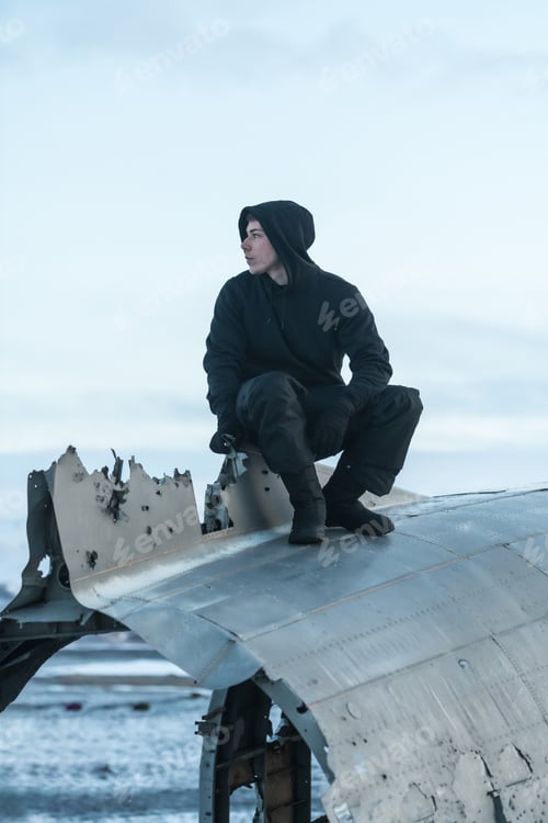 Preview: Adventurous young man sitting on the plane at Solheimasandur in winter in Iceland